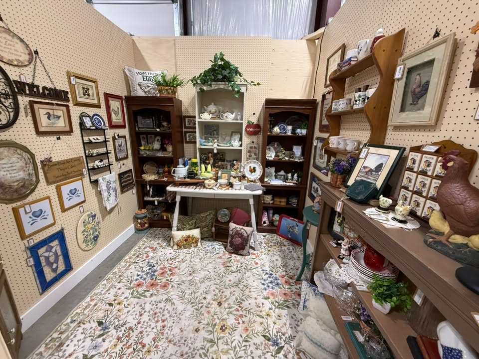 Full antiques and vintage booth with rooster decor, framed art, and a floral rug