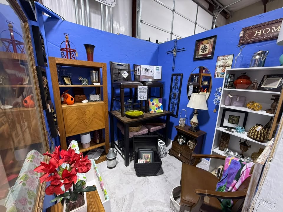 Home decor booth with wood furniture, table lamps, a mirror, and a HOME sign