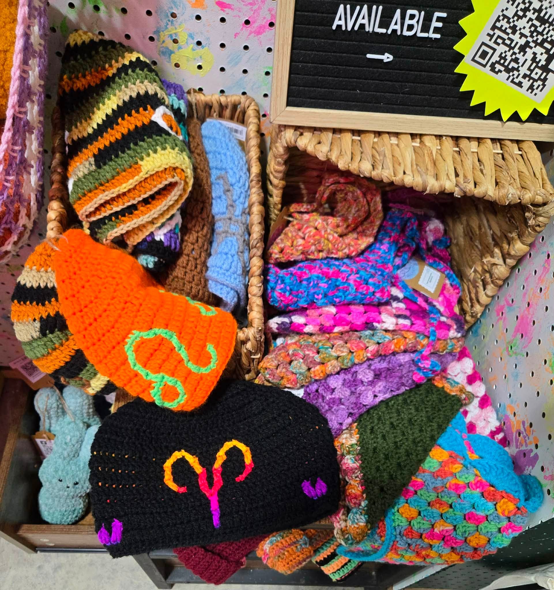Colorful handmade crocheted beanies and blankets in a basket
